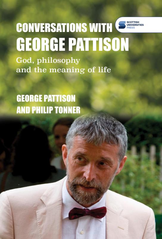 Photo of George Pattison wearing a light suit and red bowtie, with a blurred background of trees and other greenery.